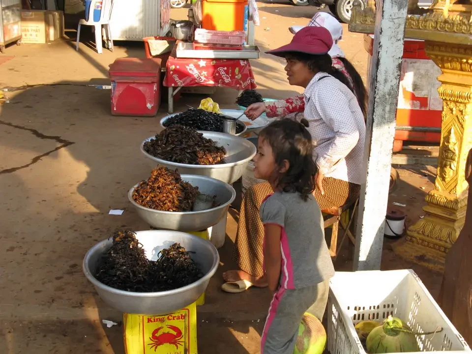 Bambini interagiscono con venditori di cibo all'aperto in Vietnam o Cambogia.