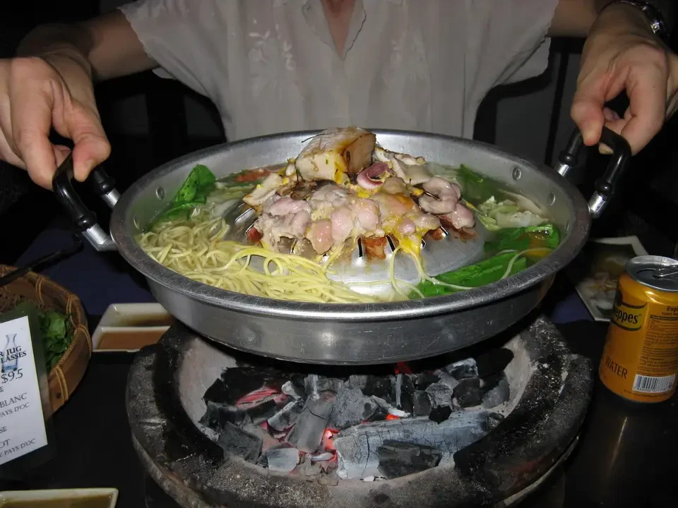 Un piatto di pasta con frutti di mare viene cucinato su una griglia a carbone in Vietnam o Cambogia.