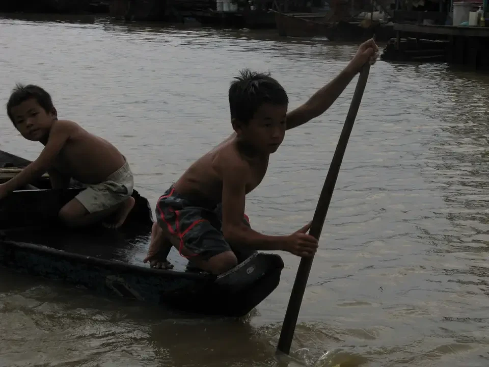 Due bambini stanno remando in una barca lungo un fiume.