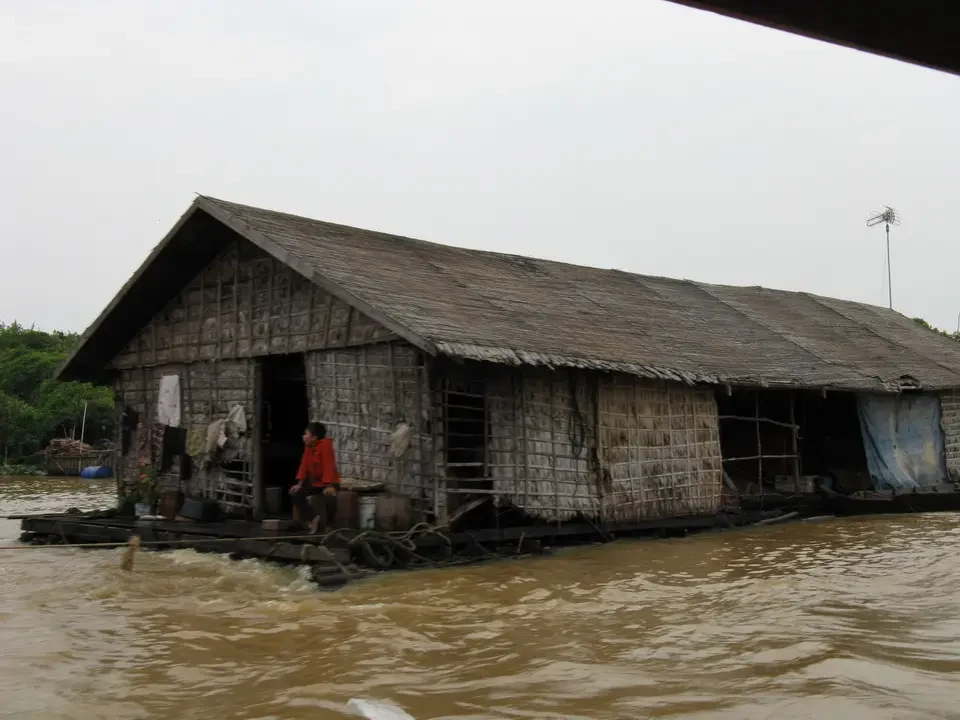 Una casa in legno galleggiante si trova in una zona fluviale fangosa.