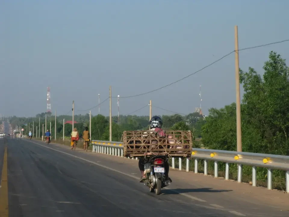 Un motociclista trasporta merci su una strada rurale in Vietnam o Cambogia. Un motociclista trasporta merci su una strada rurale in Vietnam o Cambogia.