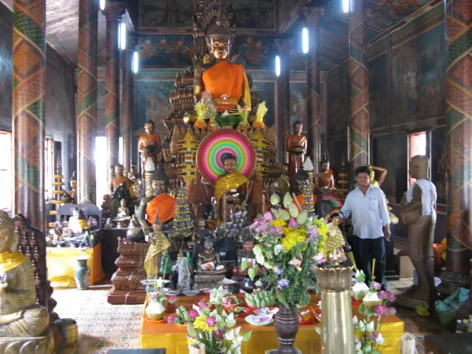 Interno di un tempio buddista in Cambogia o Vietnam con statue dorate e decorazioni floreali.