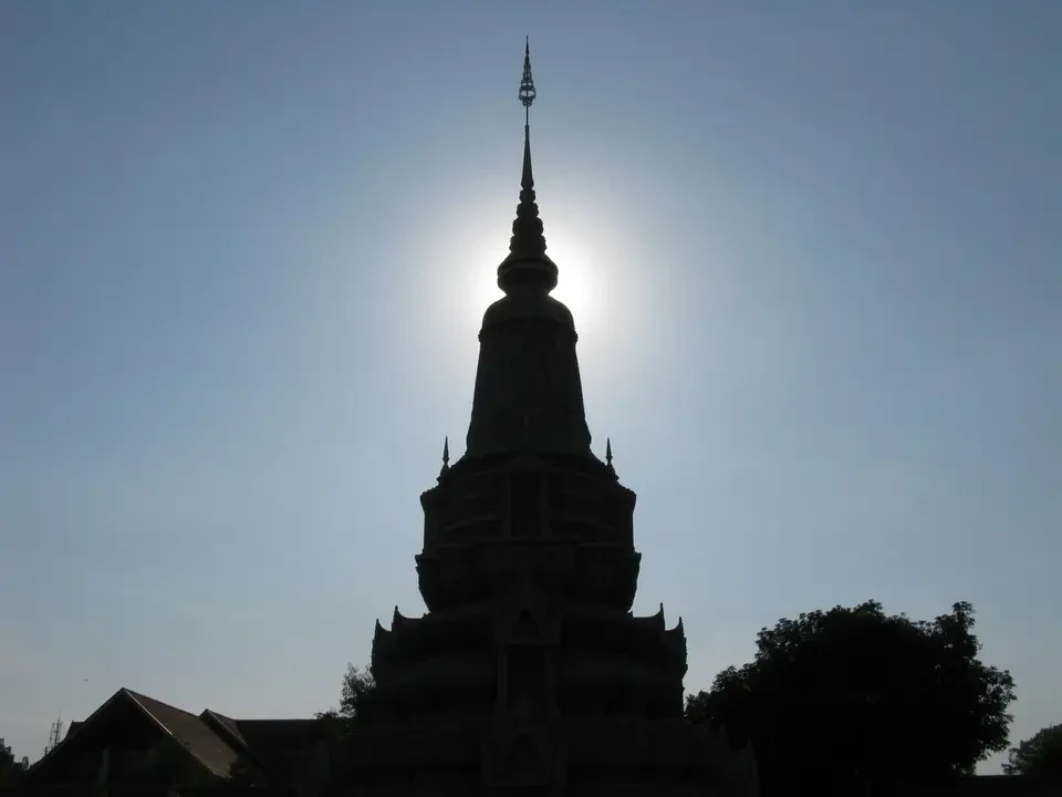 Silhouette di un tempio in pietra con guglia che si staglia contro il cielo.