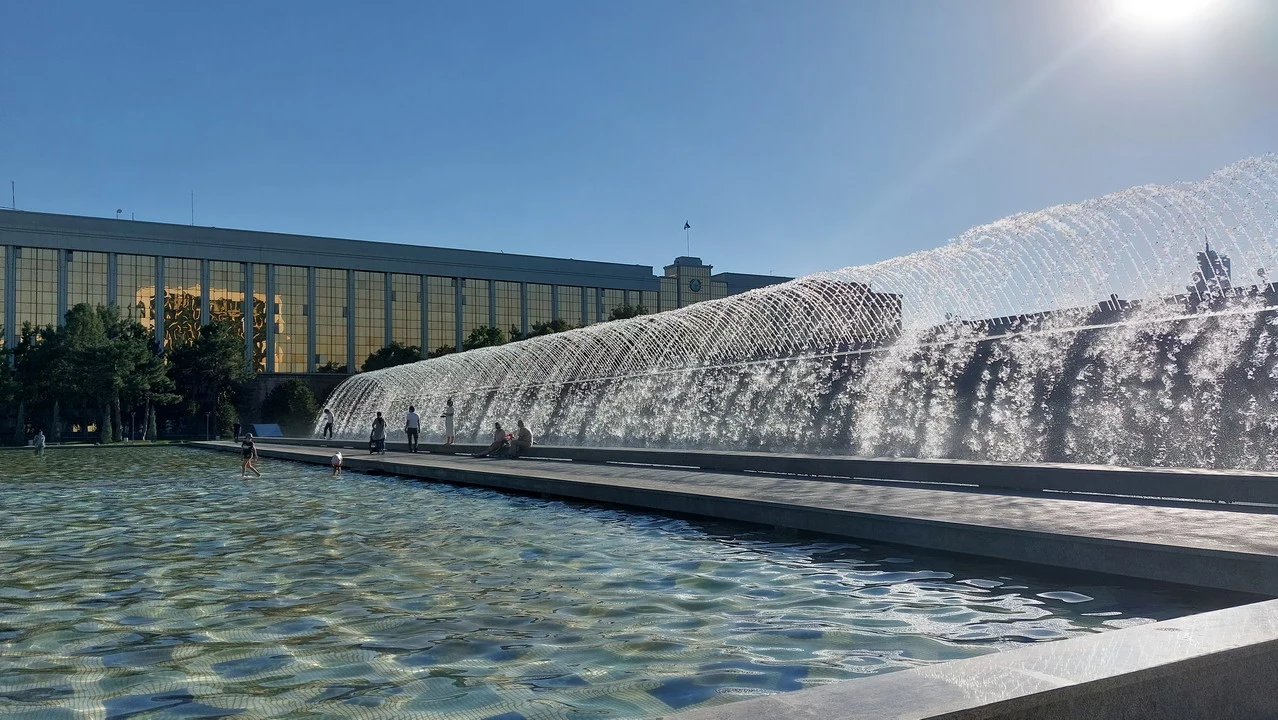 Il monumento all'Indipendenza di Tashkent con una fontana d'acqua in primo piano.