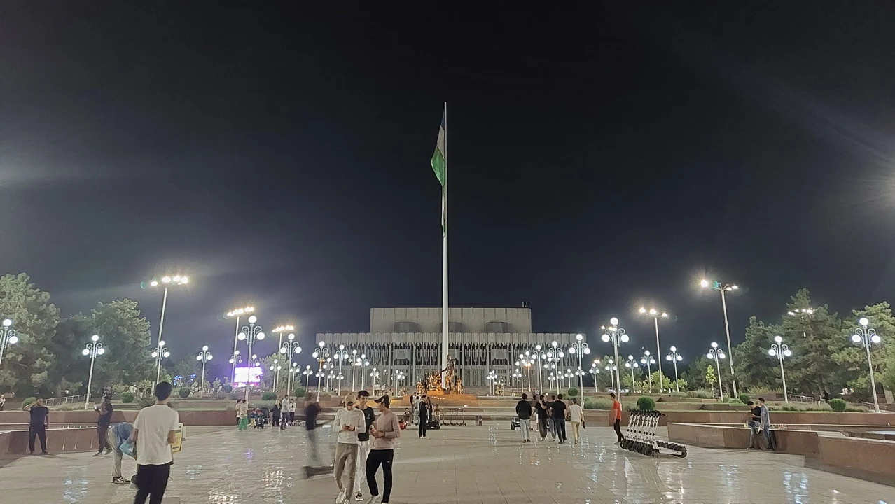Vista notturna del Palazzo dell'Amicizia a Tashkent con una bandiera issata.