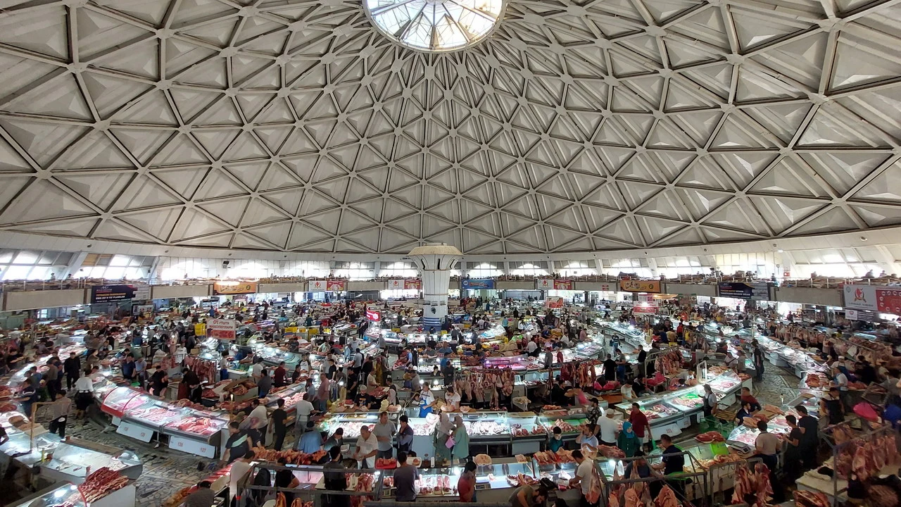 Un vasto mercato coperto pieno di carne si estende sotto una cupola interna.