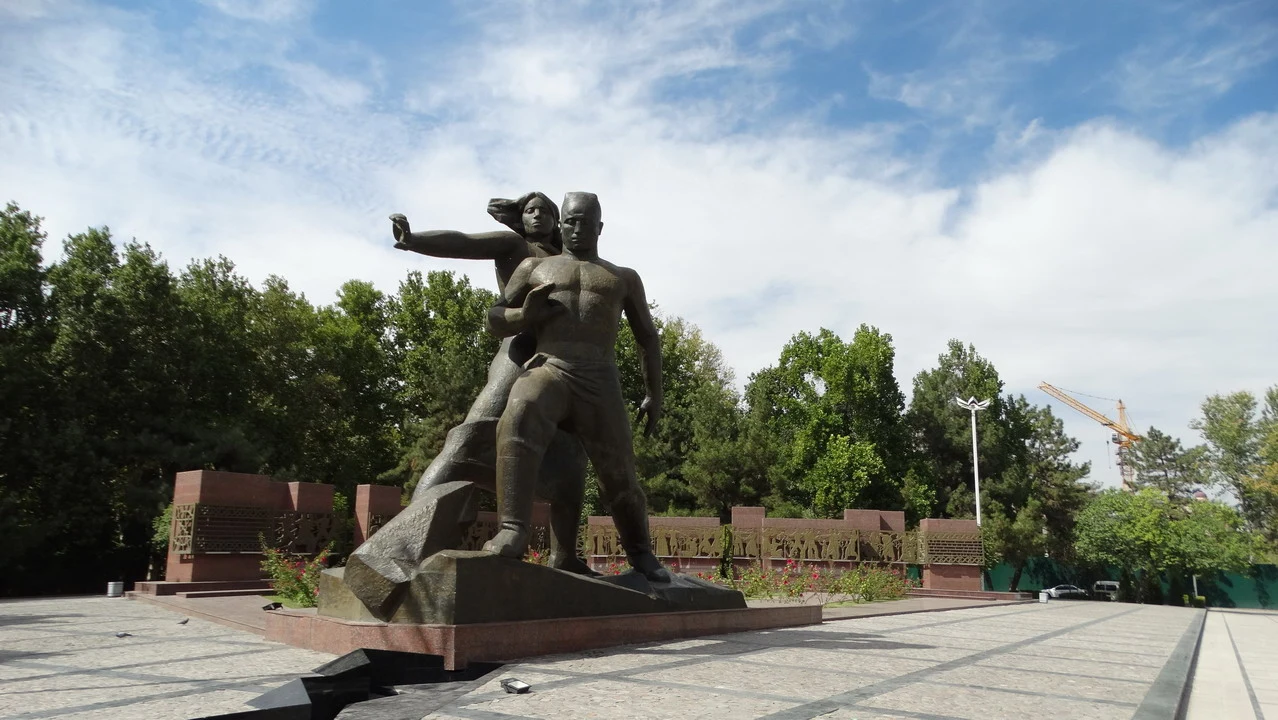 Monumento commemorativo eretto in bronzo con due figure umane che interagiscono.