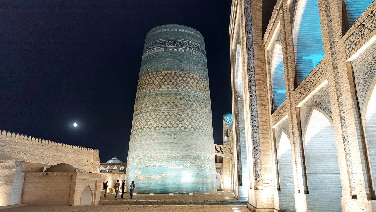 Vista notturna di una struttura in mattoni con archi decorati in Uzbekistan.