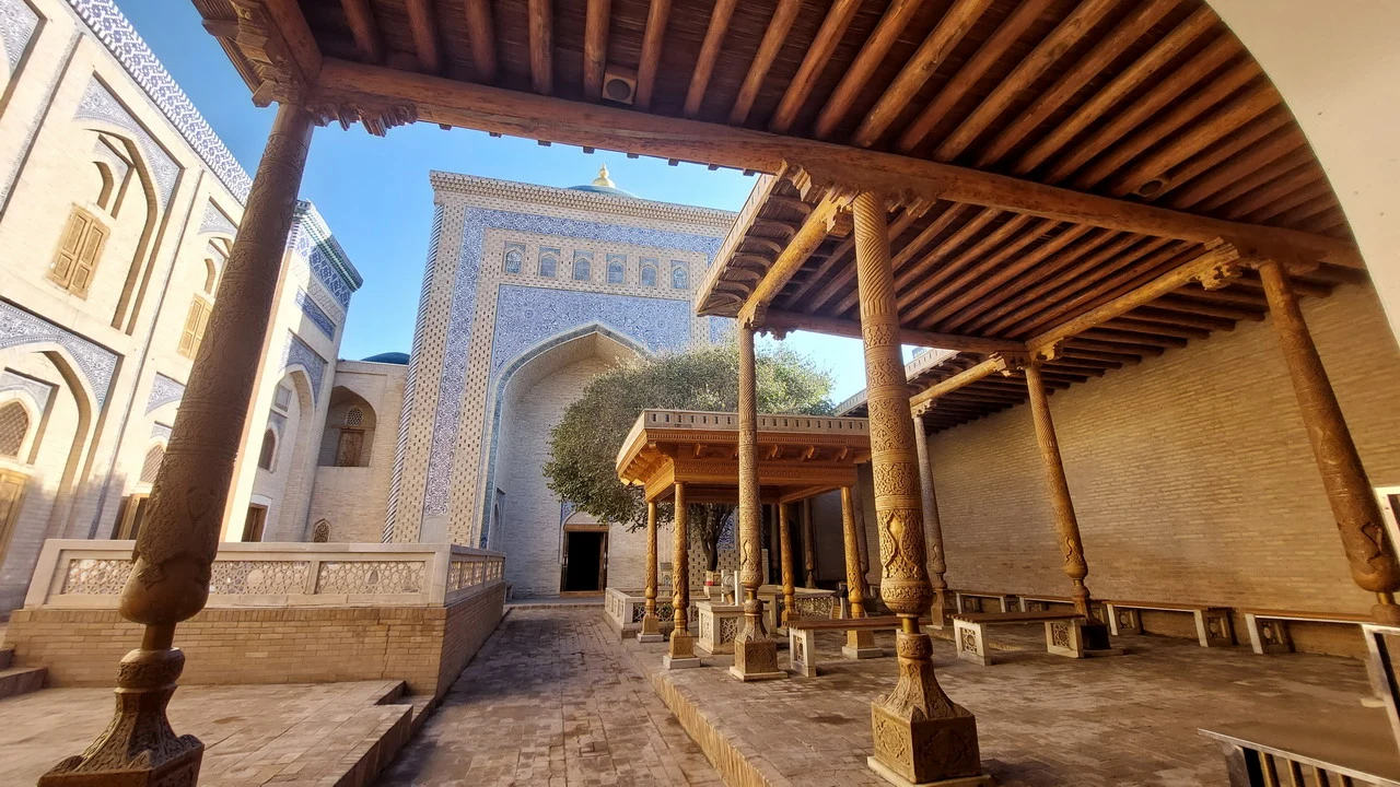 Cortile interno di un edificio storico in mattoni con colonne e tettoie in pietra.