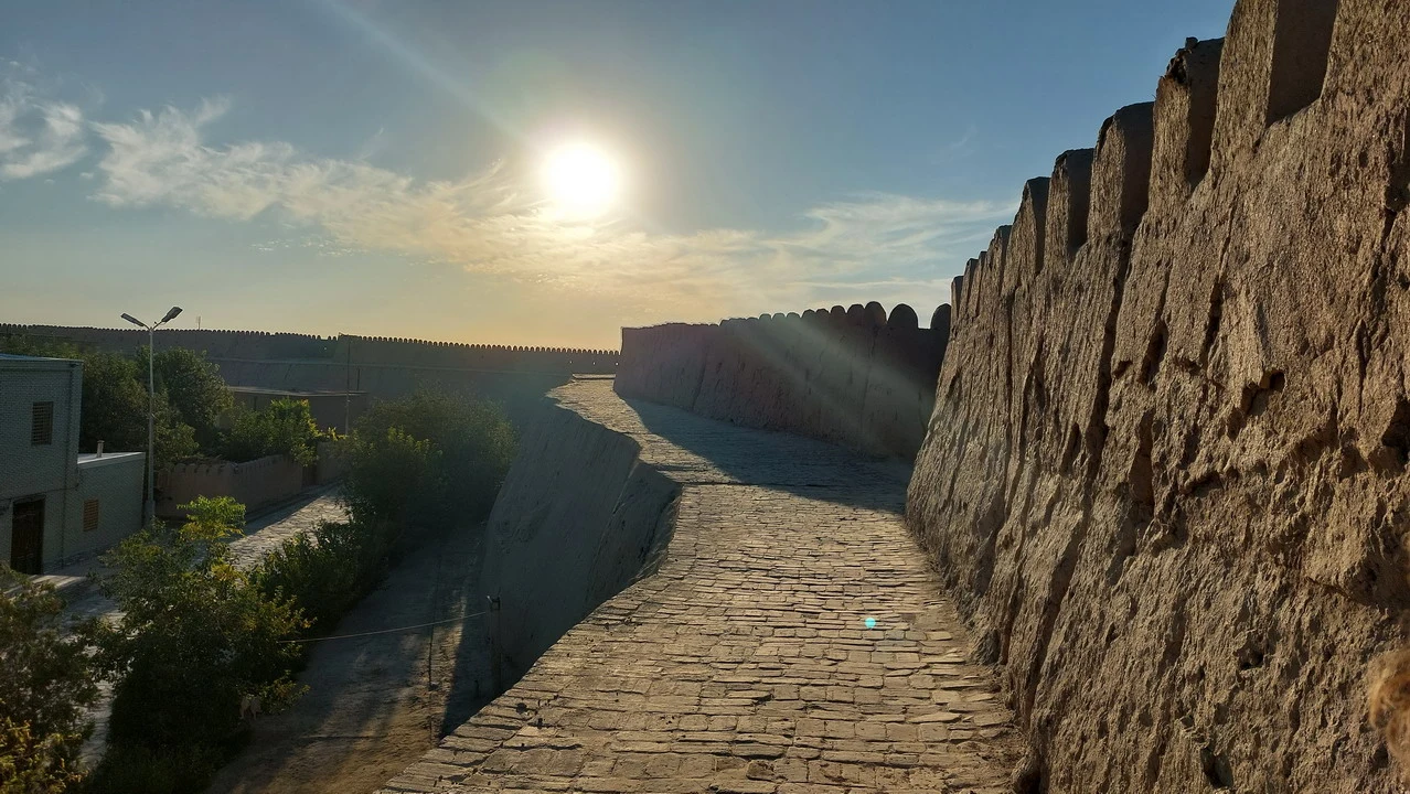 Mura di cinta antiche in pietra che si estendono lungo un paesaggio arido.