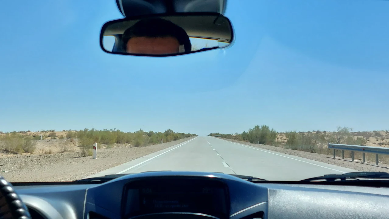 Una strada asfaltata si estende attraverso un paesaggio arido dell'Asia Centrale.