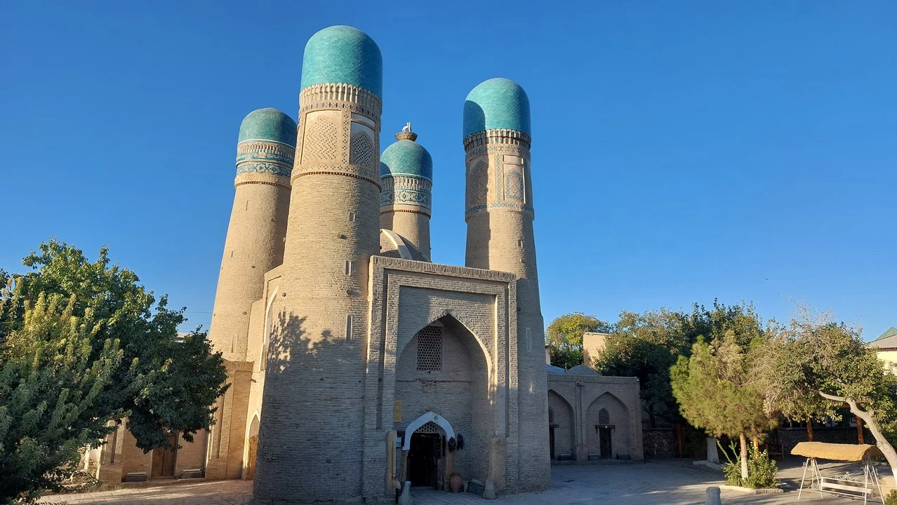 Moschea di Bukhara con cupole blu e mura in mattoni chiari.