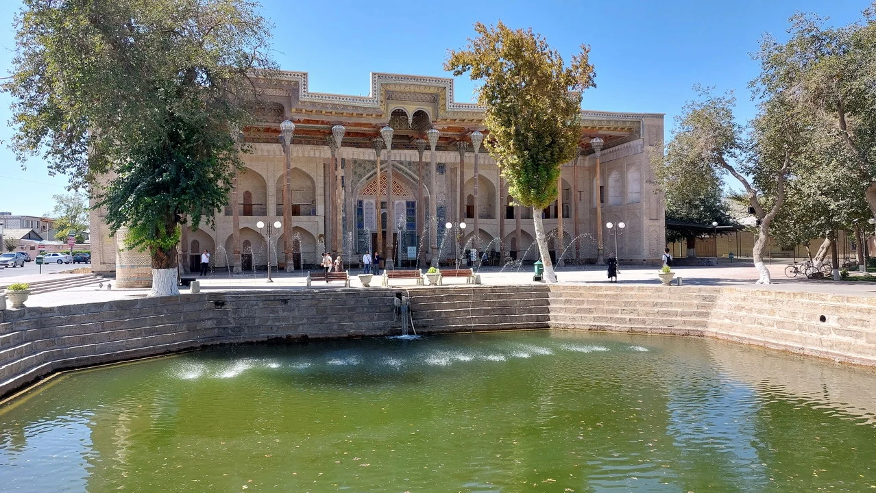 Una piazza con fontana e alberi in un contesto storico dell'Asia Centrale.