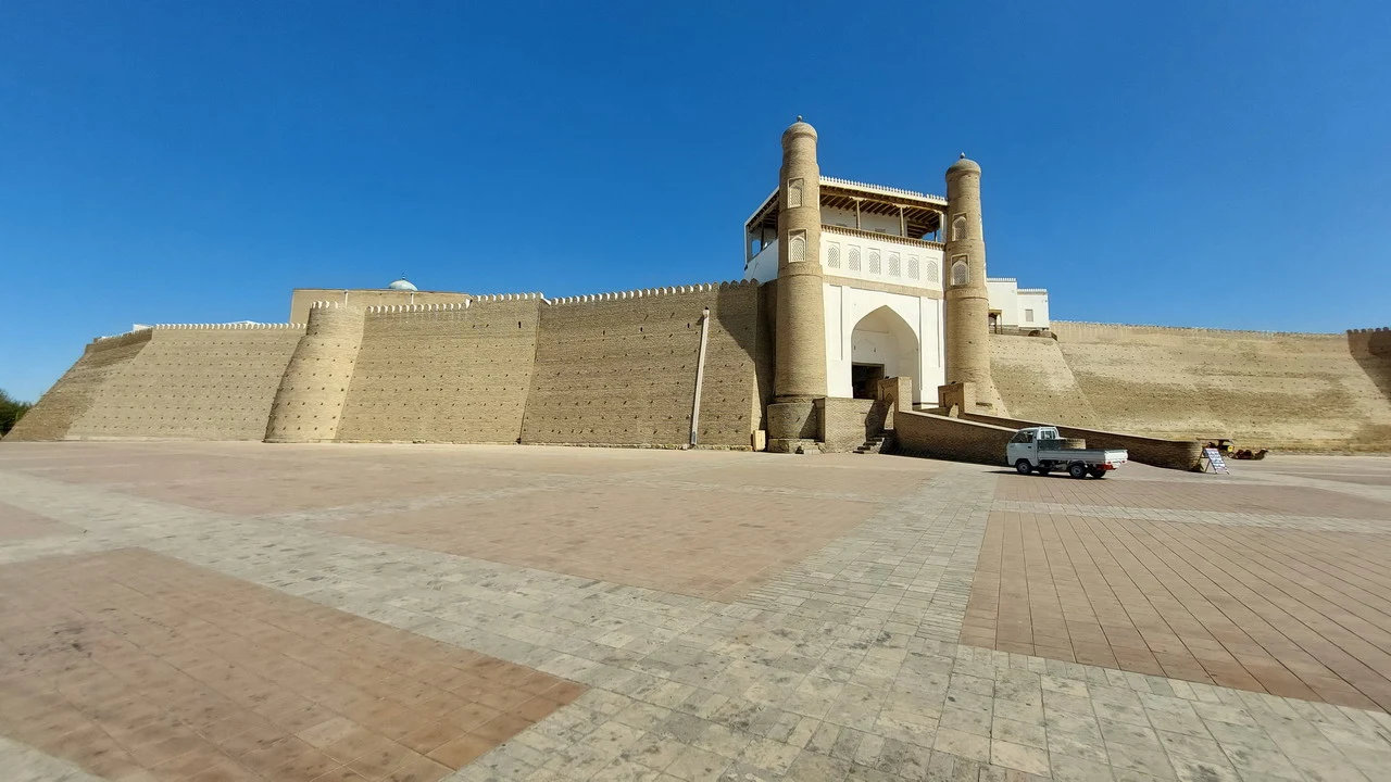 Vista esterna del Registan di Samarcanda con mura imponenti e architetture in mattoni dorati.