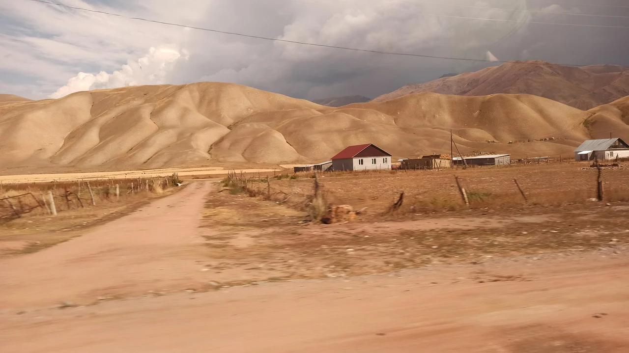 Un sentiero sterrato attraversa un paesaggio collinare secco in Asia Centrale.
