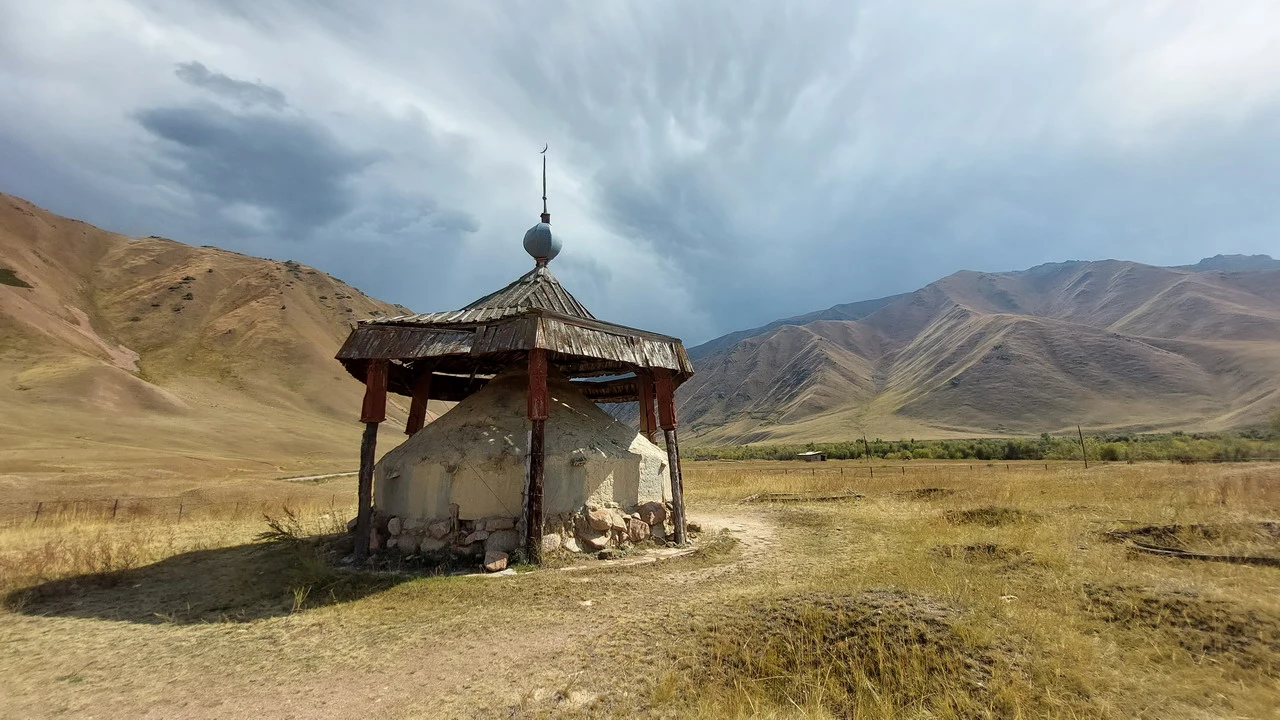 Un edificio tradizionale in pietra con tetto a pagoda si staglia su un paesaggio montano arido.