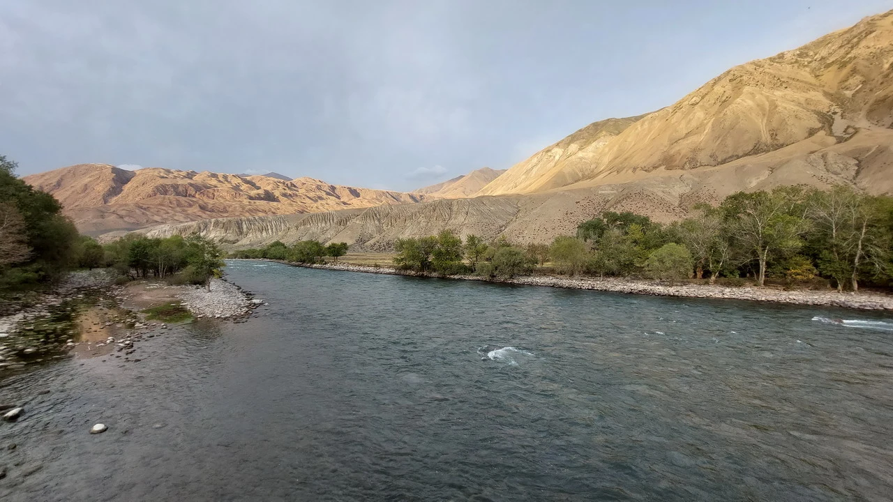 Un fiume scorre attraverso un paesaggio montuoso e arido dell'Asia Centrale.