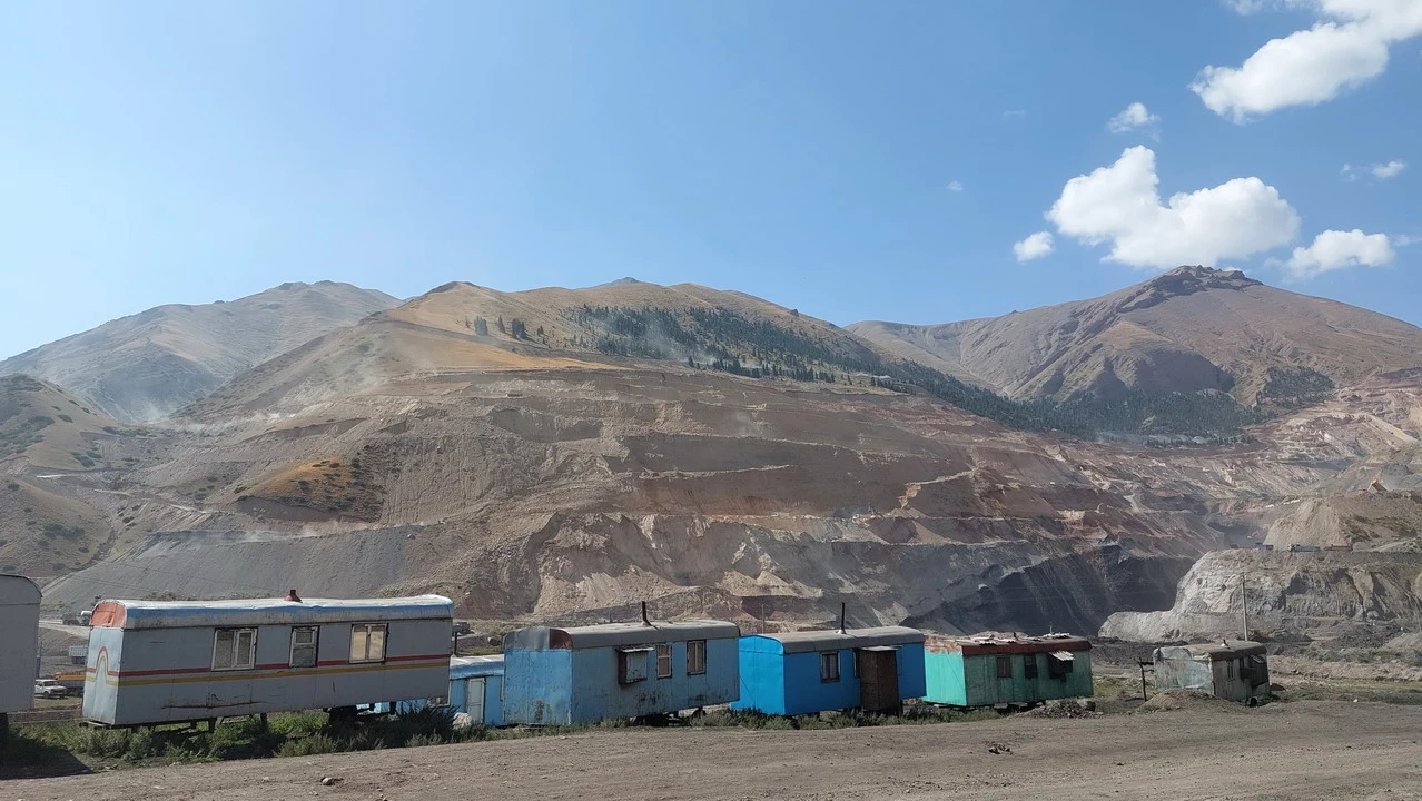 Paesaggio montano con strutture in legno nel vallone di Djumgal vicino a una miniera di carbone.