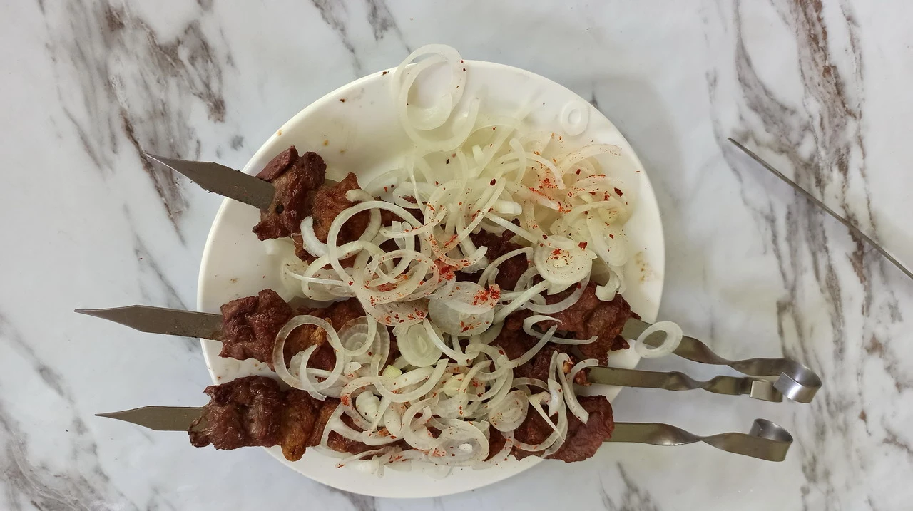 Un piatto di kushk (sashlik) con cipolle fresche è disposto su un piatto.