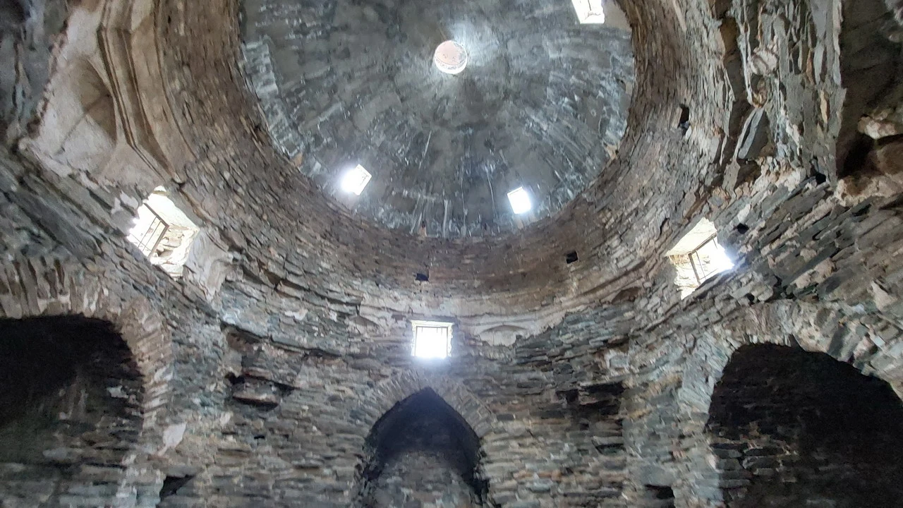 Interno di un caravanserraglio in pietra con volte a botte illuminate da finestre.