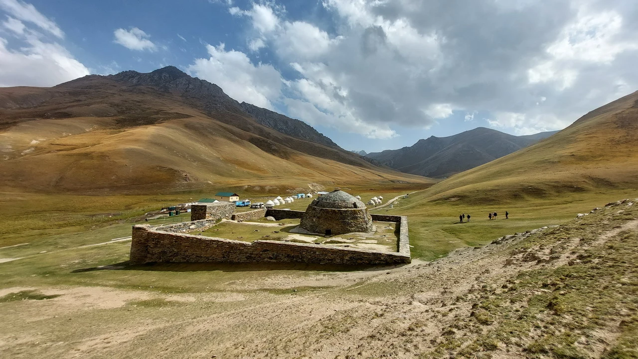 A caravanserraglio in pietra si staglia nel paesaggio montano dell'Asia Centrale.