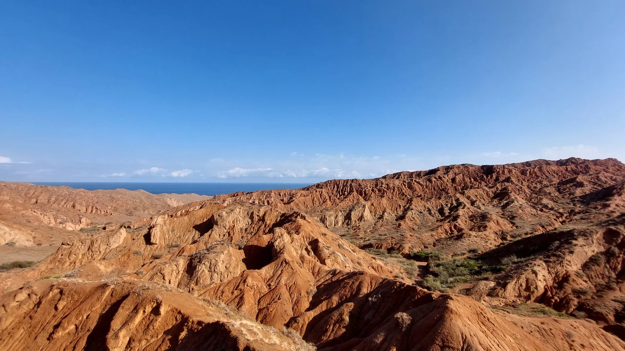 Paesaggio desertico di canyon rossi sotto un cielo azzurro.