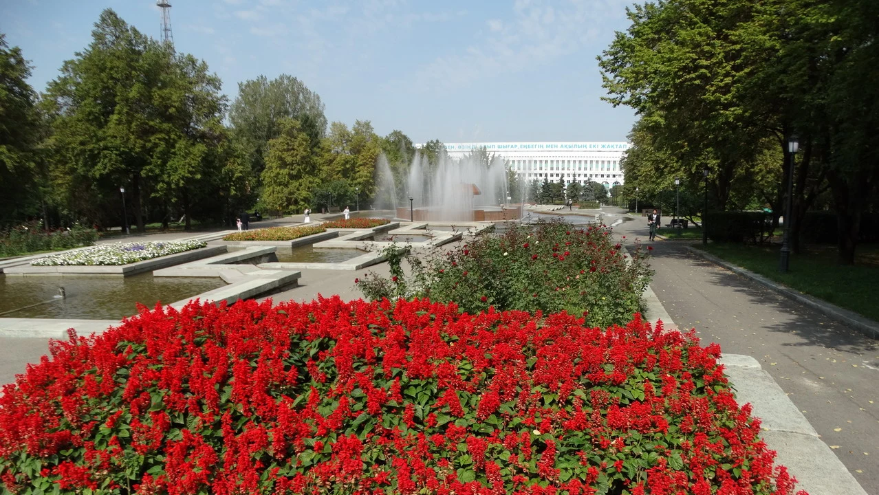 Un parco florido con alberi e una fontana in primo piano.