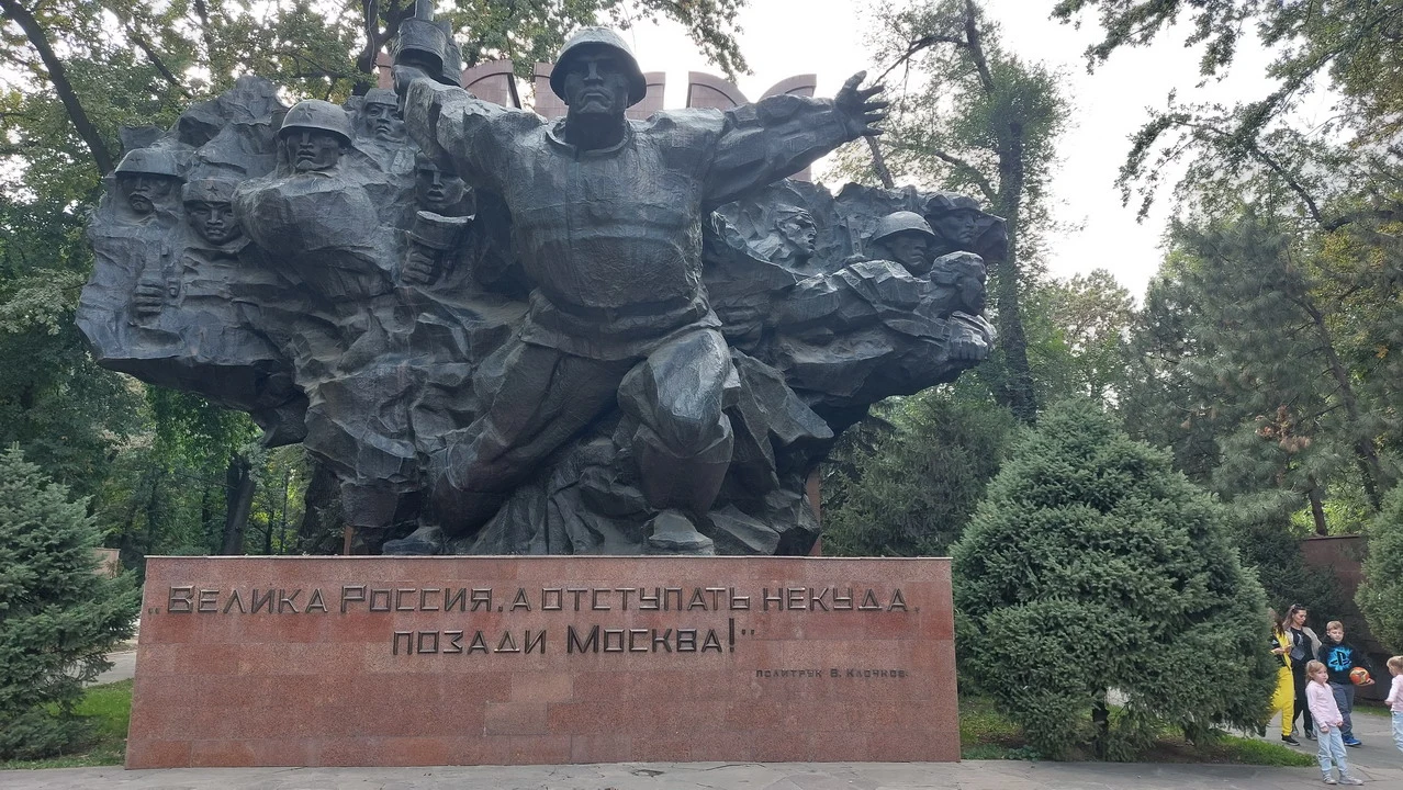 Statua monumentale di un uomo che sorregge una fila di soldati in un contesto storico.