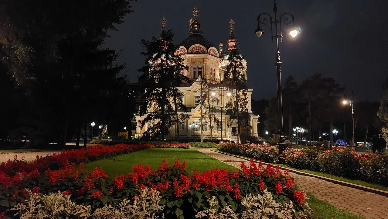 Vista notturna di un palazzo storico con giardini fioriti in Asia Centrale.