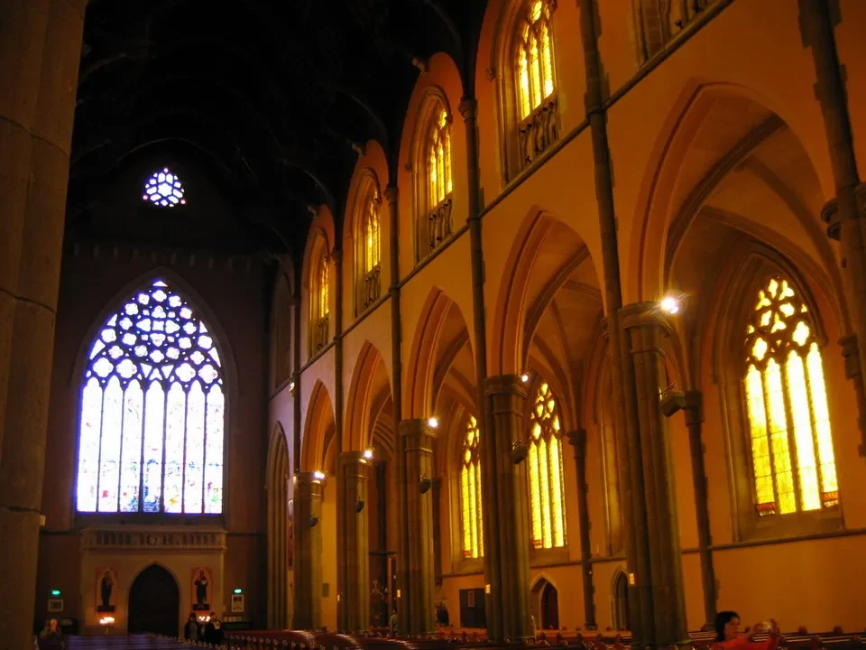 Interno maestoso di una cattedrale con arcate e finestre a vetrate.