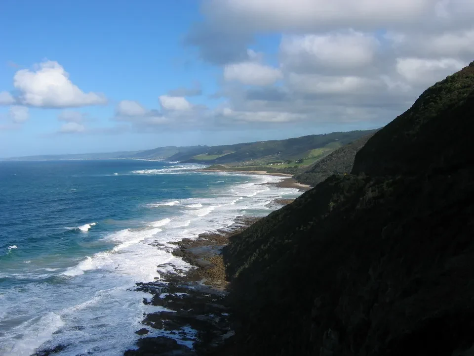 Paesaggio costiero lungo la Great Ocean Road in Australia con onde che si infrangono sulla riva rocciosa.