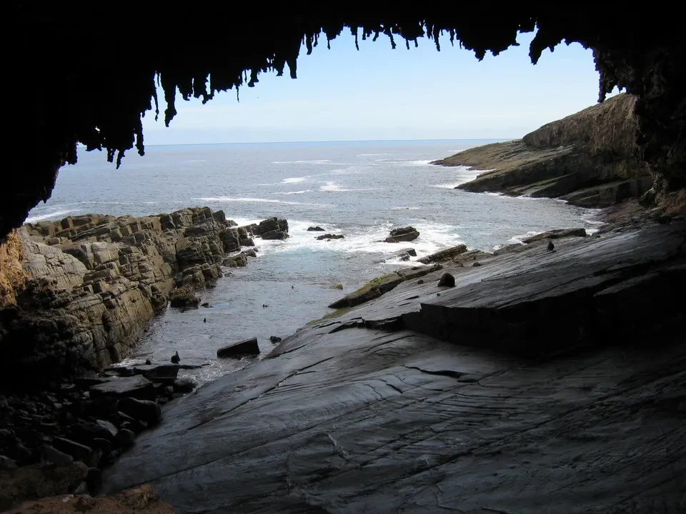 Una formazione rocciosa oscura incornicia una vista del mare aperto.