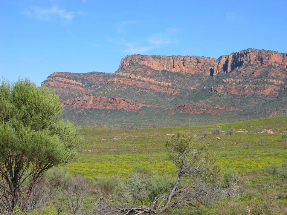 Paesaggio del paesaggio australiano con formazioni rocciose rossastre sotto un cielo azzurro.