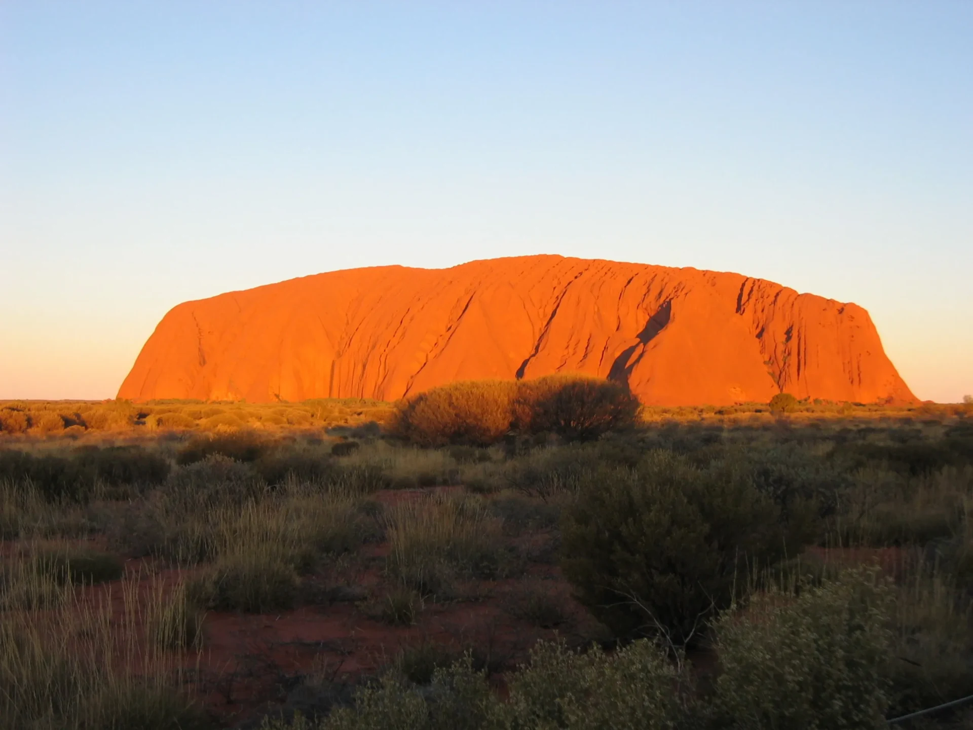 Una formazione rocciosa arancione è visibile contro il cielo durante il tramonto nell'Outback australiano.