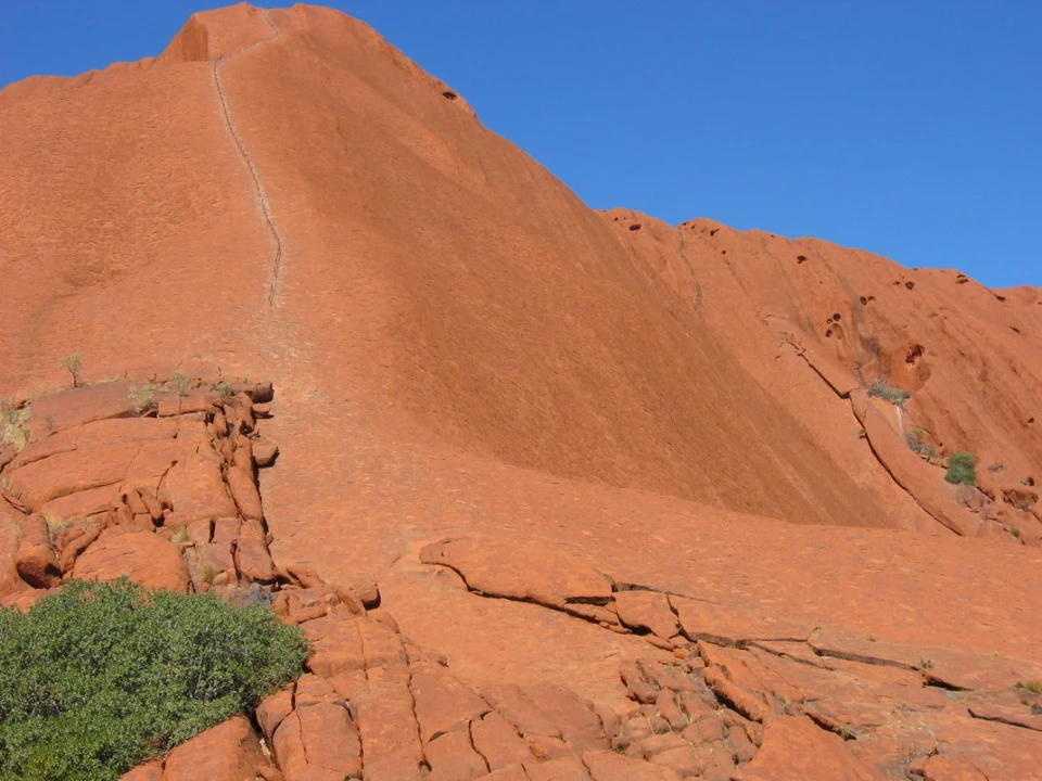 Una formazione rocciosa rossa e ondulata si estende sotto un cielo azzurro in Australia.