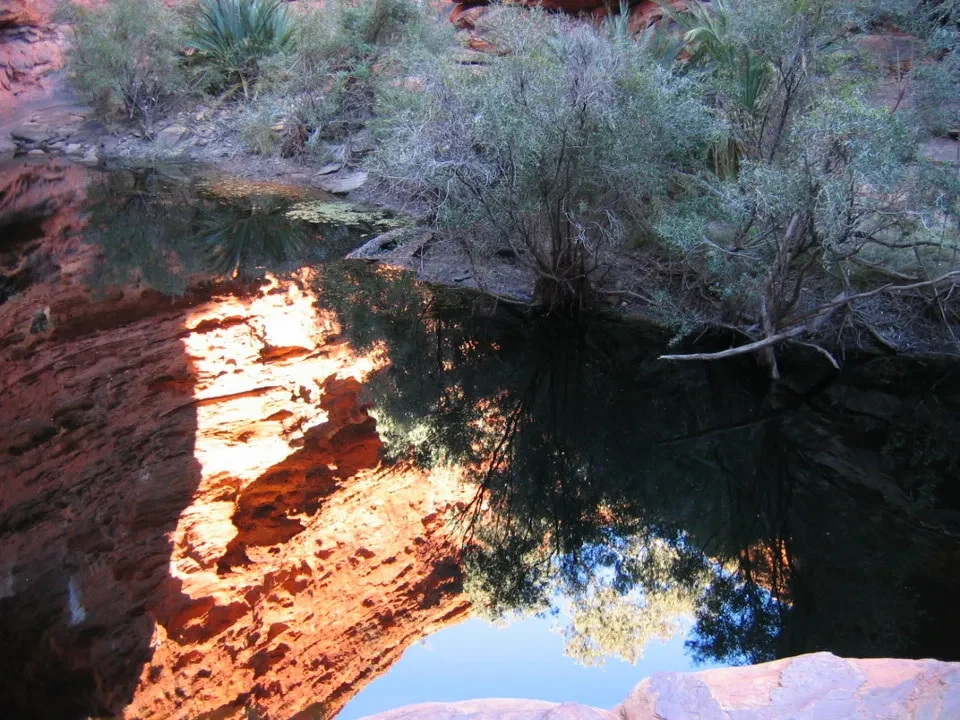 Un riflesso di alberi e rocce nell'acqua in un paesaggio australiano.