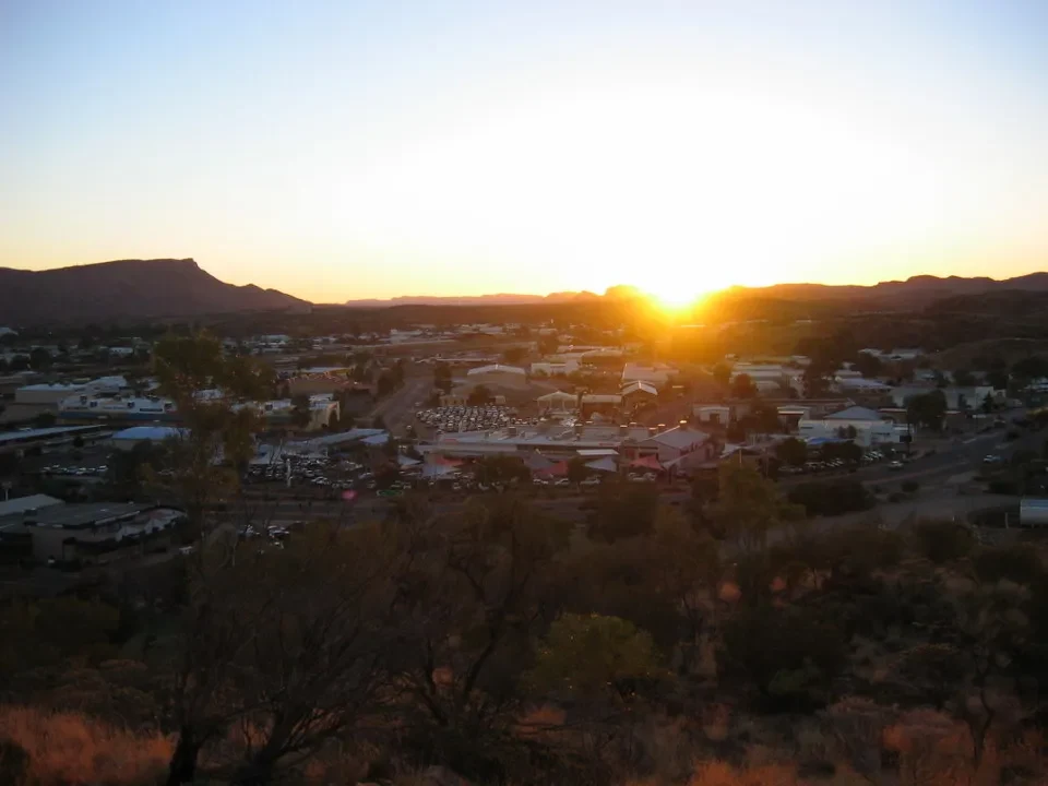 Tramonto dorato su un paesaggio australiano con una città sottostante.