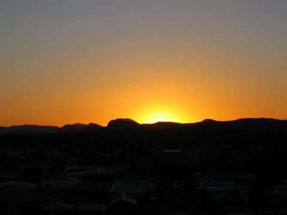 Tramonto spettacolare sopra un paesaggio australiano con silhouette di colline scure.