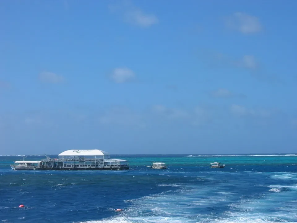 Una piattaforma galleggiante in legno è visibile sull'acqua blu sotto un cielo limpido.