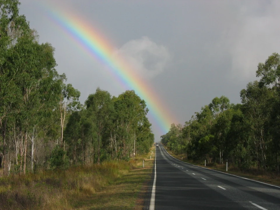 Un arcobaleno si staglia sopra una strada di campagna australiana.