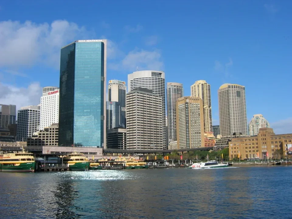 Panorama del centro di Sydney con edifici moderni e un fiume in primo piano.