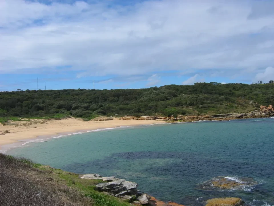 Paesaggio costiero australiano con acqua turchese e spiaggia sabbiosa.