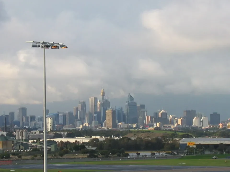 Skyline di Sydney visibile sopra la città e l'aeroporto in primo piano.