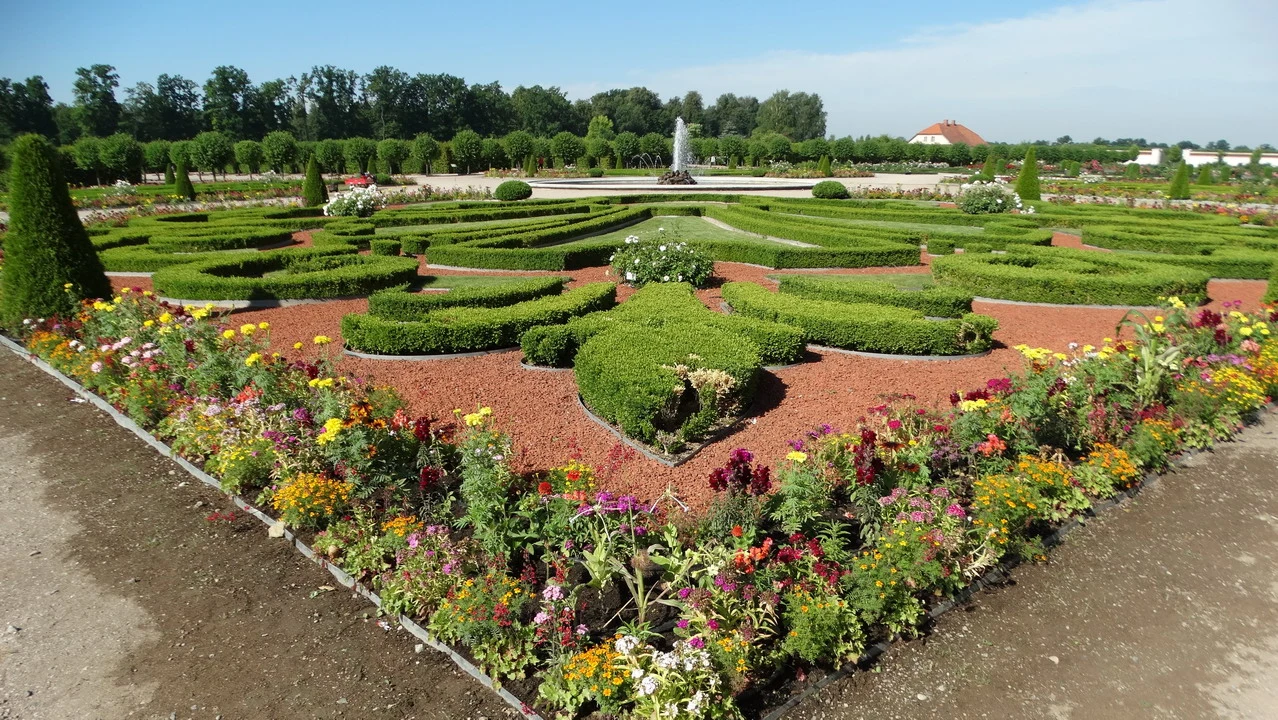 Giardino fiorito con aiuole bordate di fiori colorati sotto un cielo sereno.