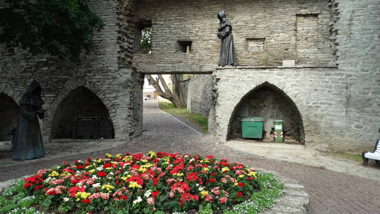 Antico muro di pietra con archi e fiori colorati in primo piano.