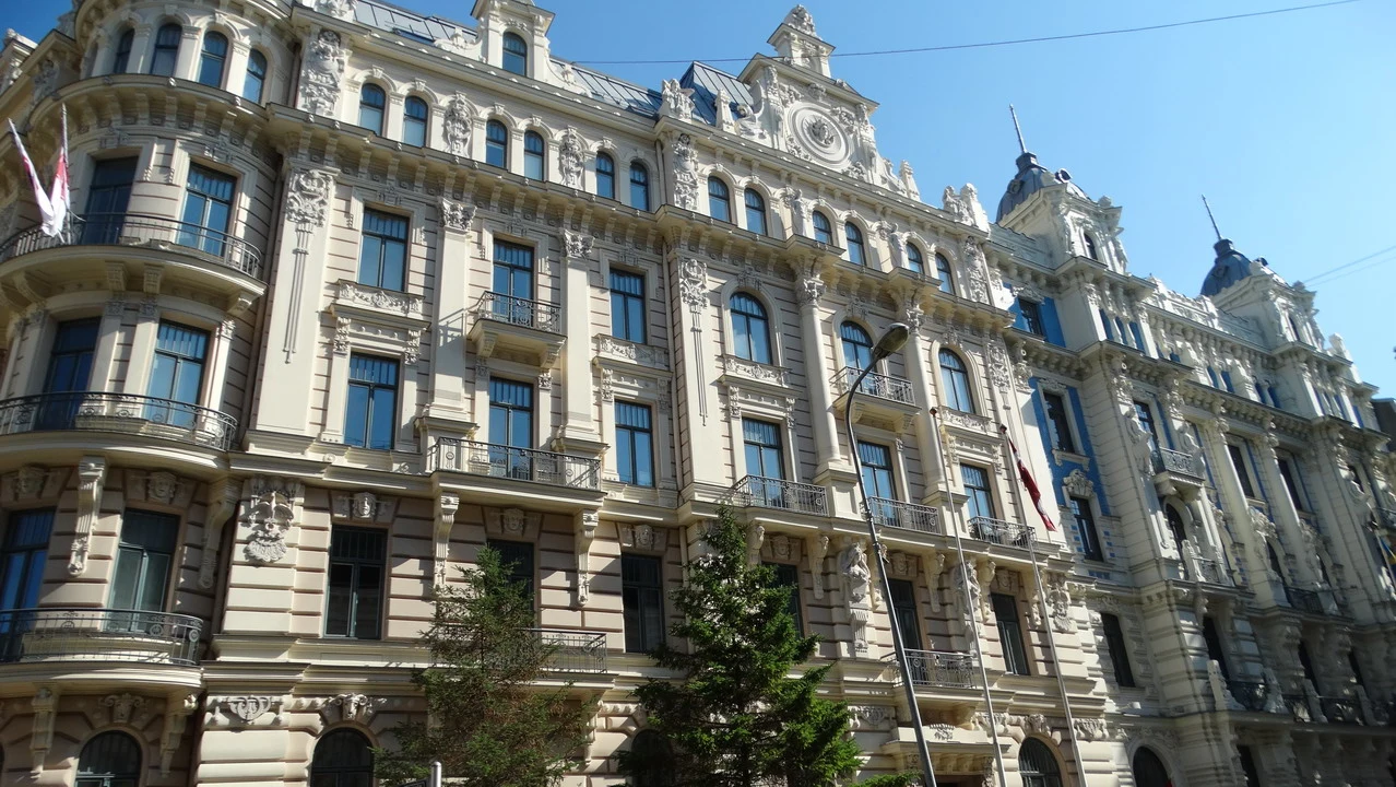 Edificio storico in stile classico con facciata chiara e balconi lungo una strada cittadina.