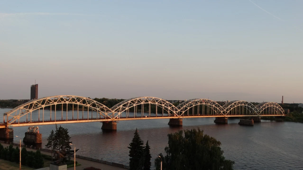 Un ponte ad arco si estende sopra l'acqua durante il tramonto in una città baltica.
