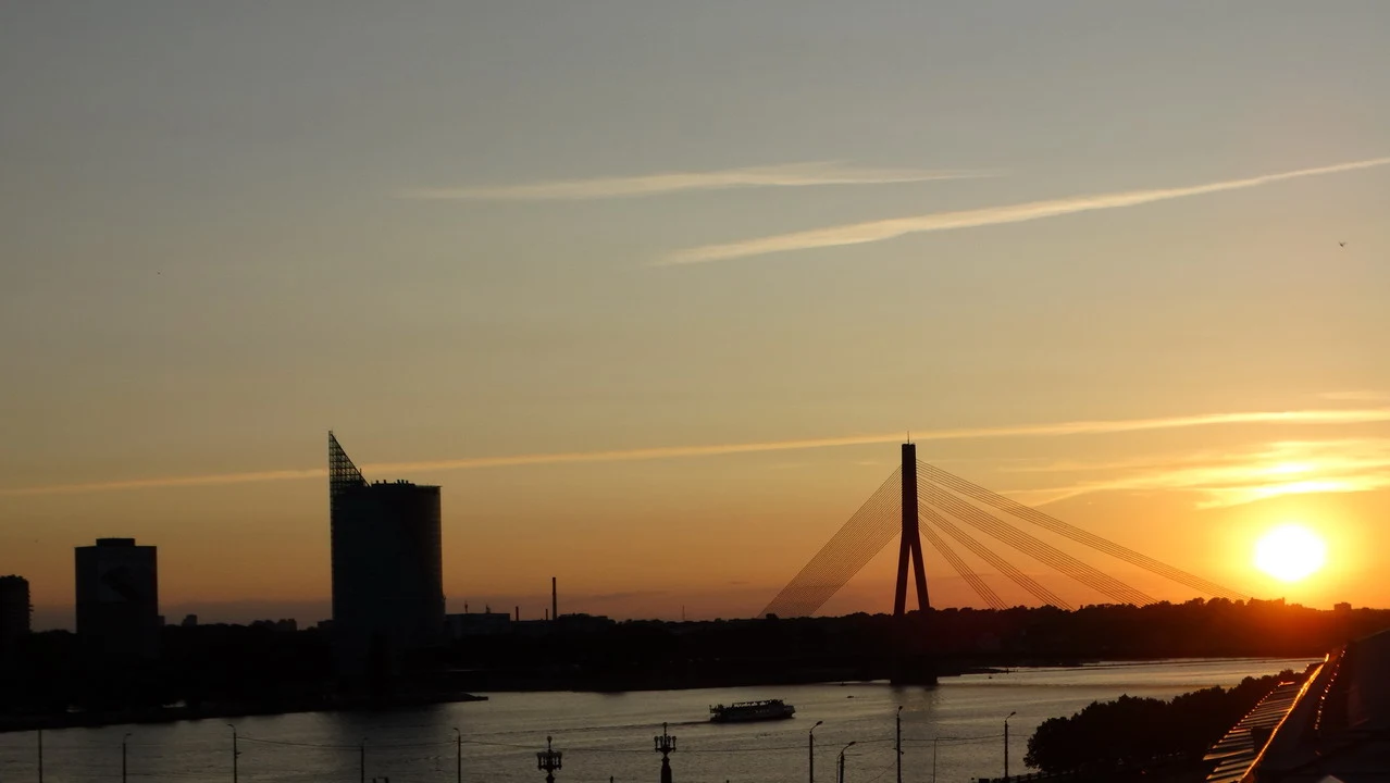 Tramonto sul ponte di Riga con il sole che tramonta sull'acqua.