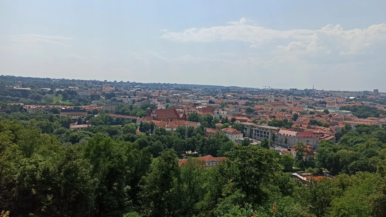 Vista panoramica di una città con tetti rossi e vegetazione lussureggiante.