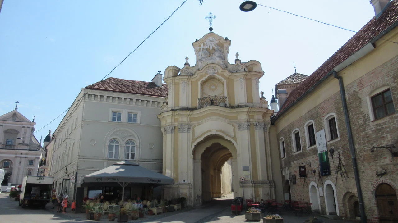 Una veduta di una strada storica con edifici in stile barocco e un portale d'accesso.